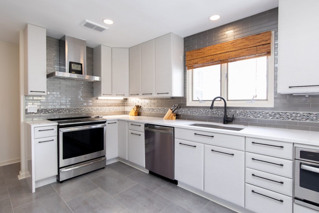 New modern kitchen remodel with white cabinets, gray tile floor, and gray tile backsplash.