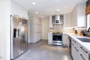Newly designed kitchen with light gray floors, white cabinets, and stainless steel appliances.