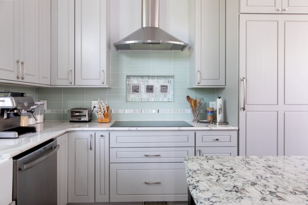 White cabinets and a stainless steel stove hood in a remodeled kitchen