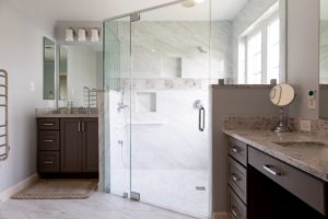 New bathroom remodel with gray cabinets and glass-enclosed shower.