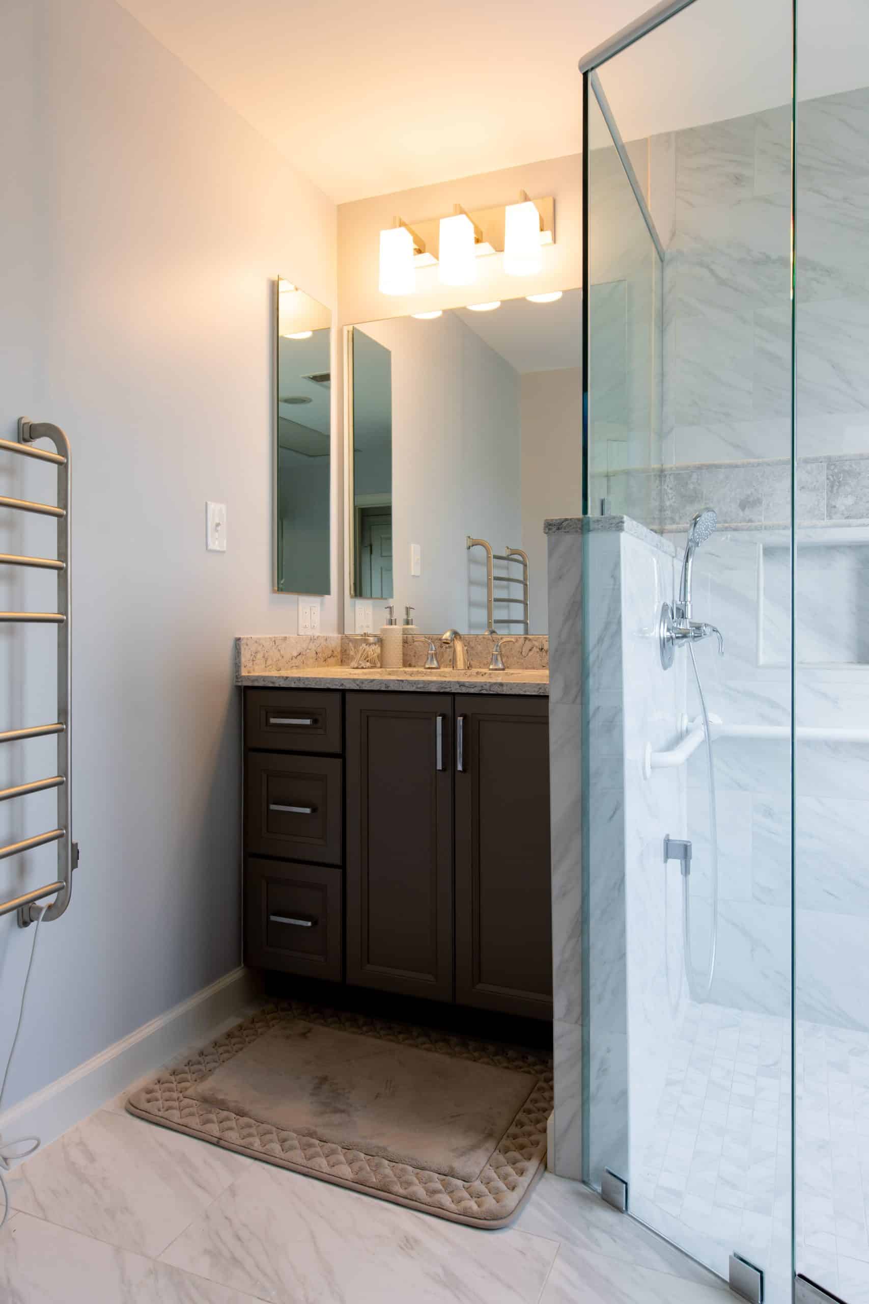 a bathroom with a walk in shower next to a dark cabinet sink