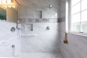 Remodeled bathroom with white tile walls and floors, large window, and standing shower.